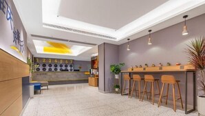Un moderno vestíbulo de hotel con zona de bar, asientos y una pantalla de reloj.