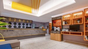 Una zona de recepción moderna con un reloj digital, una máquina de café y un televisor.