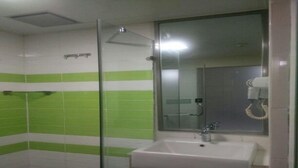 Un baño con lavamanos blanco, un espejo y cabina de ducha.