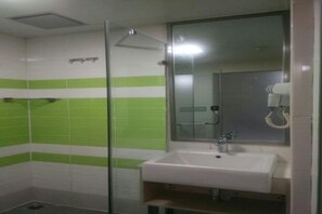 Une salle de bain avec un lavabo blanc, un miroir et un espace douche.
