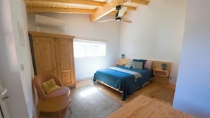 Un dormitorio con cama, una silla, armario y ventilador de techo.