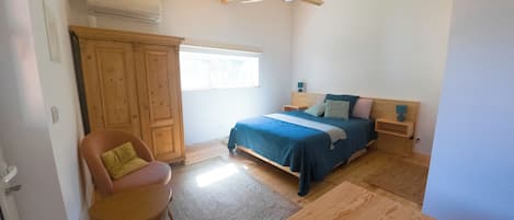 Un dormitorio con cama, una silla, armario y ventilador de techo.
