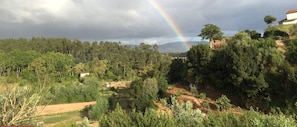 A lush landscape with a rainbow, dense forest, and a building on a hill. - Studio by the pool (Penela)