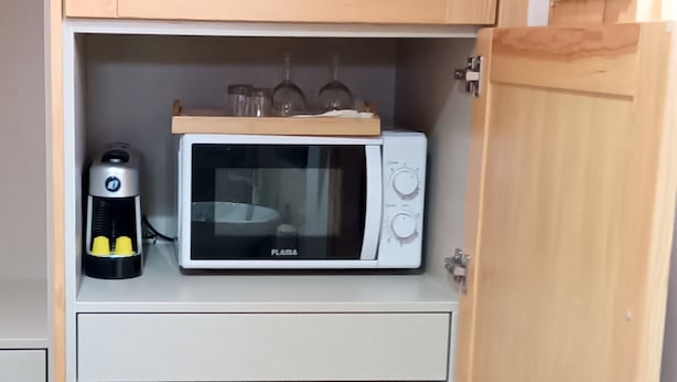 Cocina compacta con microondas, un refrigerador pequeño y cafetera.