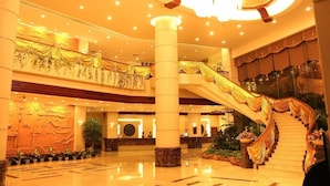 A spacious lobby with a grand staircase, multiple floors, and a reception area. - Fangzhong Sunshine Hotel (Dongguan)