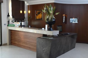 A reception desk with a modern design, a potted plant, and a framed picture on the wall. - Bomo Danai Hotel (Katerini)