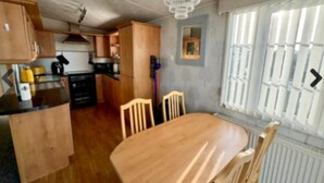 Eine Küche mit Holzausstattung, einem Esstisch mit Stühlen und einem Fenster mit Jalousien.