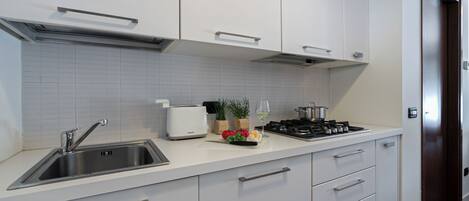 A modern kitchen with a stainless steel sink, a white countertop, a gas stove, and a toaster.