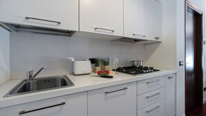 A modern kitchen with a stainless steel sink, a white countertop, a gas stove, and a toaster. - Italianway Comfort - Vico Magistretti 1 B (Milan)