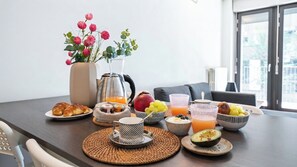 Disposição de café da manhã com croissants, frutas e bebidas sobre uma mesa.