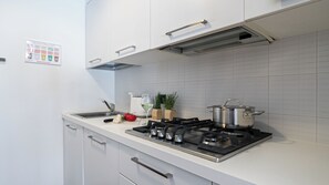 A modern kitchen with white cabinets, a stainless steel stove, and a tiled backsplash. - Italianway Comfort - Vico Magistretti 1 B (Milan)