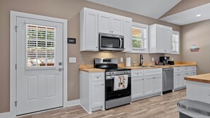 A modern kitchen with white cabinetry, a built-in oven, a microwave, and a coffee machine.
