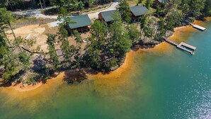 A lakeside cabin with a dock, surrounded by dense forest and clear water.