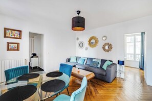 A modern living room with a sofa, chairs, a coffee table, and a dining area with a glass table and chairs. - Charming Appartement 1ch/4p - Paris 17e (Paris)