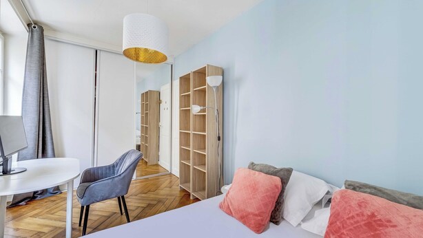 A bedroom with a bed, a desk, a chair, a wardrobe, and a hanging light fixture. - Charming Appartement 1ch/4p - Paris 17e (Paris)
