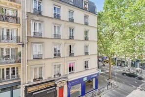 Ein mehrstöckiges Gebäude mit Balkonen, Geschäften und Straßenansicht.