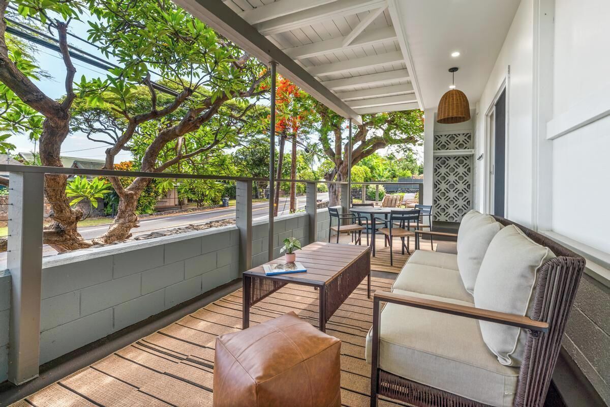 A covered outdoor seating area with a sofa, table, and chairs.
