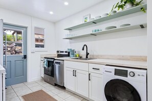 Eine moderne Küche mit Waschmaschine, Geschirrspüler und eingebautem Backofen.
