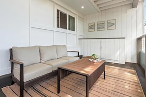 A room with a sofa, a wooden table, and a window. - New Listing, Kahaluu Surf Boutique, steps to Kahaulu (Kona)
