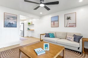 A modern living room with a sofa, coffee table, and artwork on the walls. - New Listing, Kahaluu Surf Boutique, 2-bed, 2-bath (Kona)