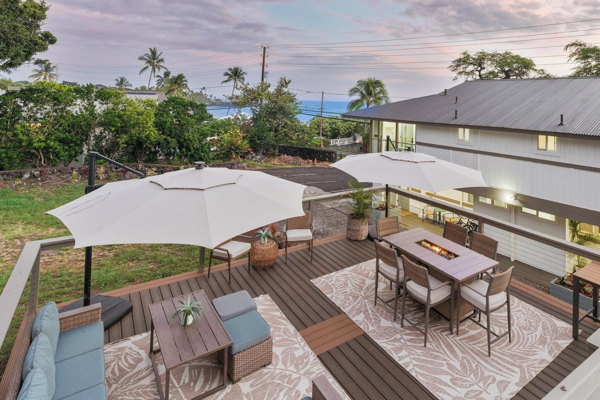 A deck with outdoor furniture, including a table and chairs, and two large umbrellas providing shade.