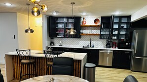 Uma cozinha moderna com ilha de mármore, armários pretos e eletrodomésticos de aço inoxidável.