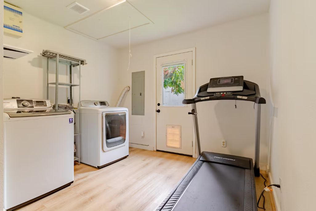 A laundry room with a washing machine, dryer, and a treadmill.
