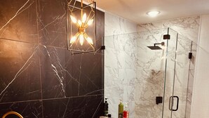 Um banheiro moderno com uma banheira de imersão, chuveiro com box de vidro e piso de mármore.