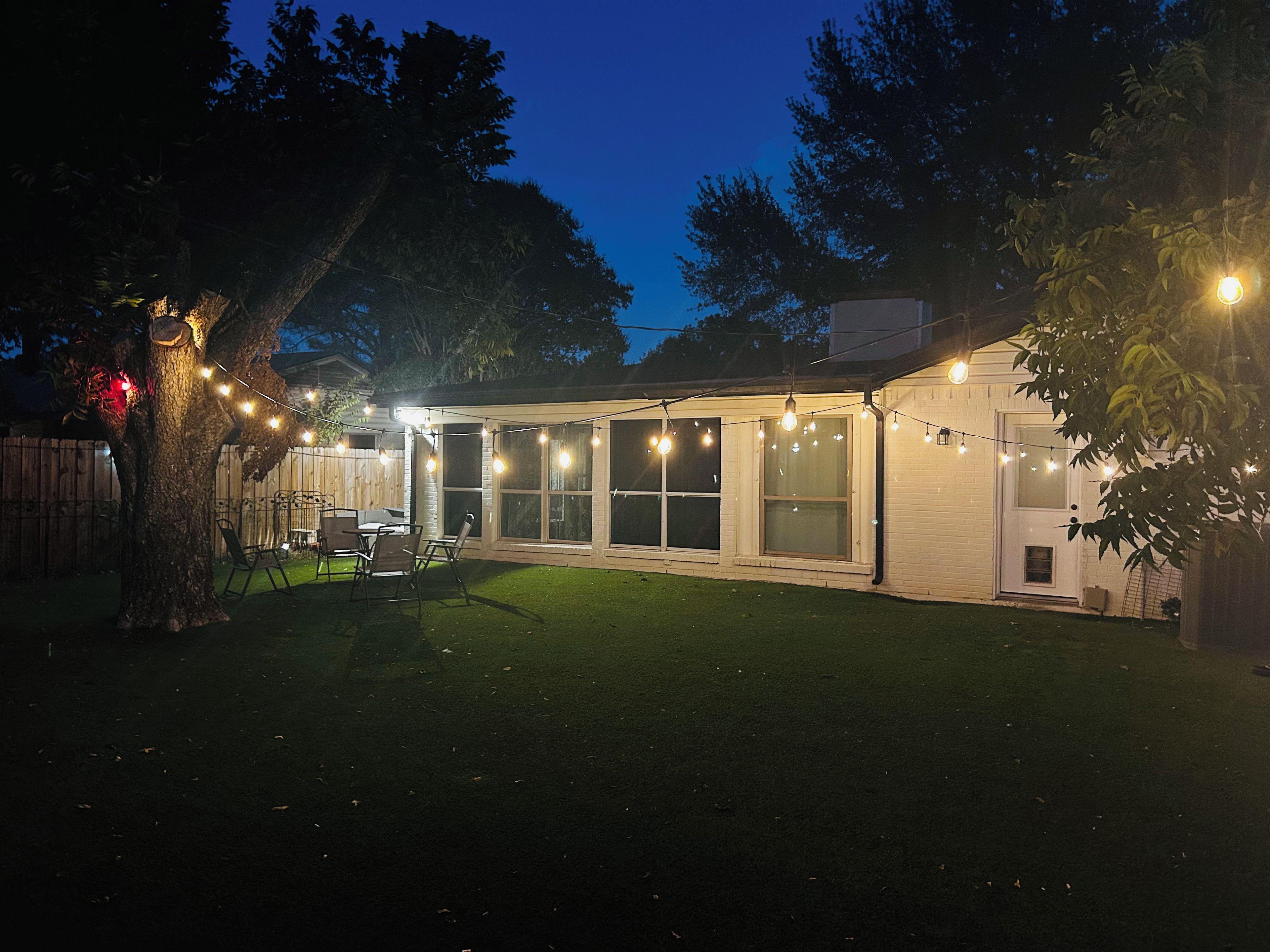 A house with a covered patio, a fenced yard, and string lights.