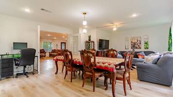 A spacious living area with a dining table, chairs, a sofa, and a TV.