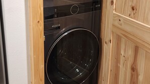 Ein kompakter Waschraum mit zwei Türen, einer Holztür sowie einer integrierten Waschmaschine und einem Trockner.
