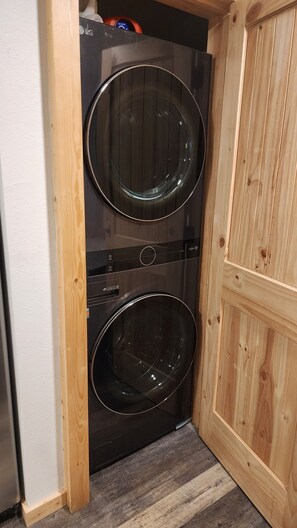 A compact, two-door laundry room with a wooden door and a built-in washer and dryer. - Fully Remodeled 2Bed 2Bath Downtown Condo 3 Blocks From Lake Walk to Everything (McCall)