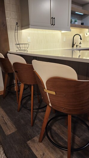 A modern kitchen with a white countertop, a black faucet, and wooden chairs. - Fully Remodeled 2Bed 2Bath Downtown Condo 3 Blocks From Lake Walk to Everything (McCall)