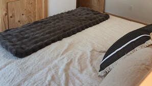 Ein Schlafzimmer mit einem Bett, einem Deckenventilator, Holztüren und einem an der Wand befestigten Fernseher.