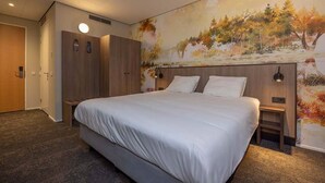 Ein Hotelzimmer mit einem großen Bett, einem Kleiderschrank, einem Nachttisch und einem Wandbild.
