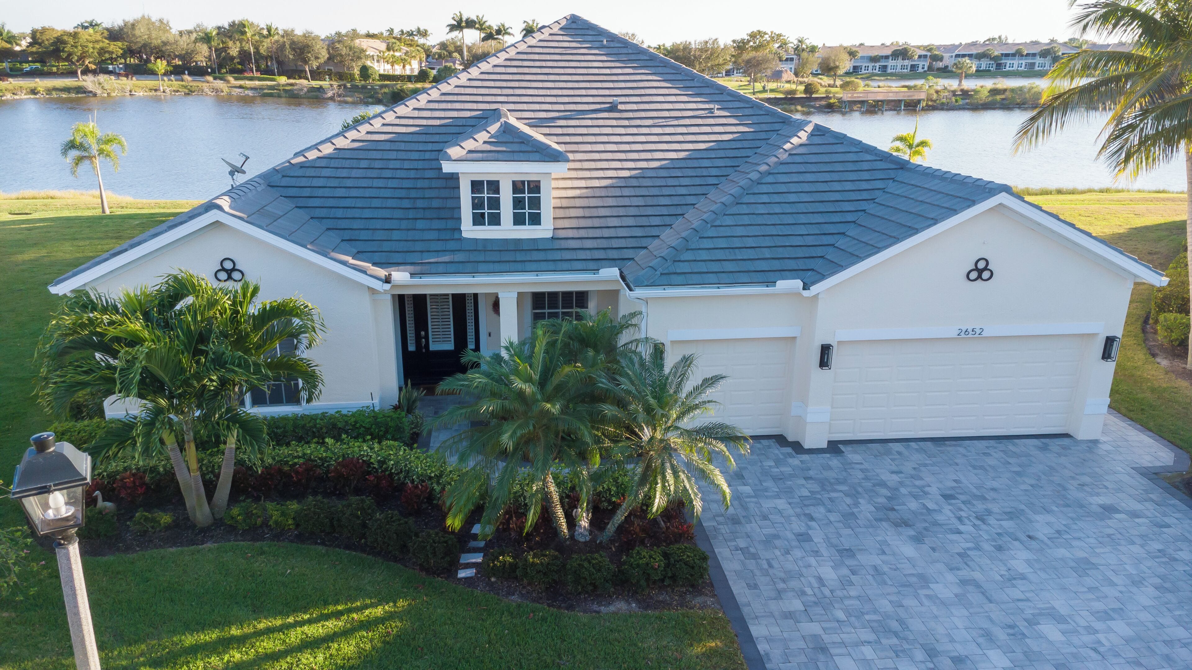 A single-story house with a garage, a covered front porch, and a landscaped yard with palm trees.