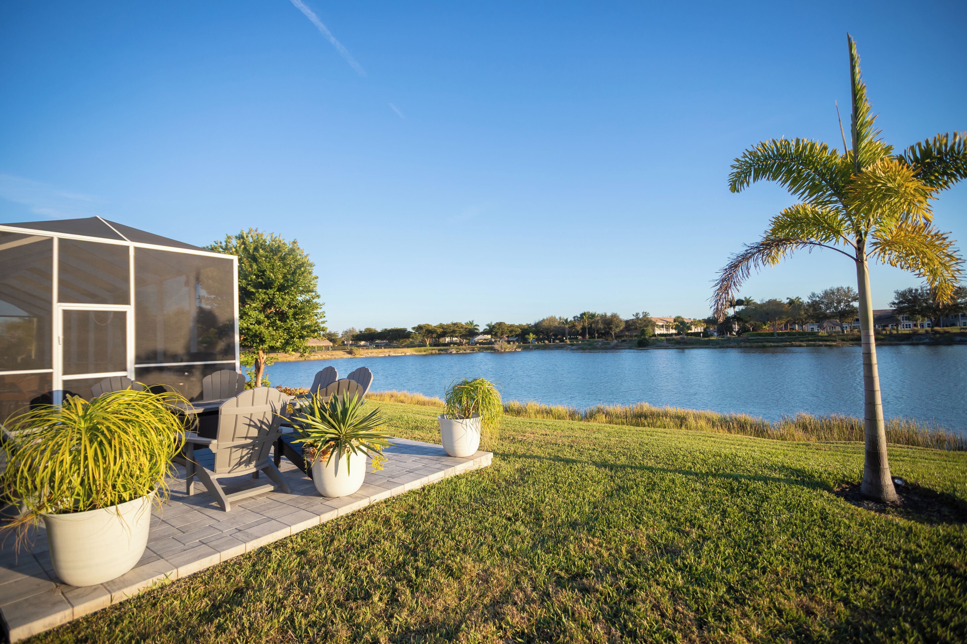 Un patio junto al lago con mobiliario exterior, un área de estar cubierta y vistas al lago.