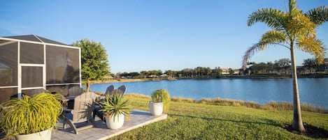Un patio junto al lago con mobiliario exterior, un área de estar cubierta y vistas al lago.