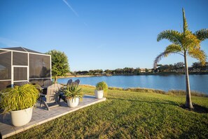 A lakeside patio with outdoor furniture, a covered seating area, and a view of the lake. - The Ultimate Waterfront Retreat | 5BR • Pool & Spa • Resort Amenities (Cape Coral)