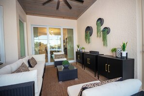 A modern outdoor living area with a sofa, a coffee table, and a cabinet with plants. - The Ultimate Waterfront Retreat | 5BR • Pool & Spa • Resort Amenities (Cape Coral)