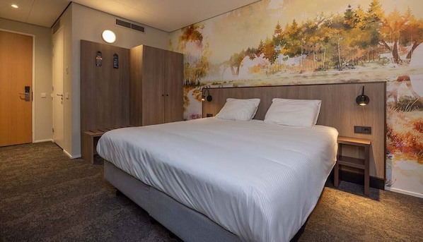 Een hotelkamer met een groot bed, een kledingkast, een nachtkastje en een muurschildering.
