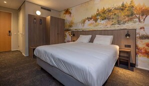 A hotel room with a large bed, a wardrobe, a nightstand, and a wall mural.