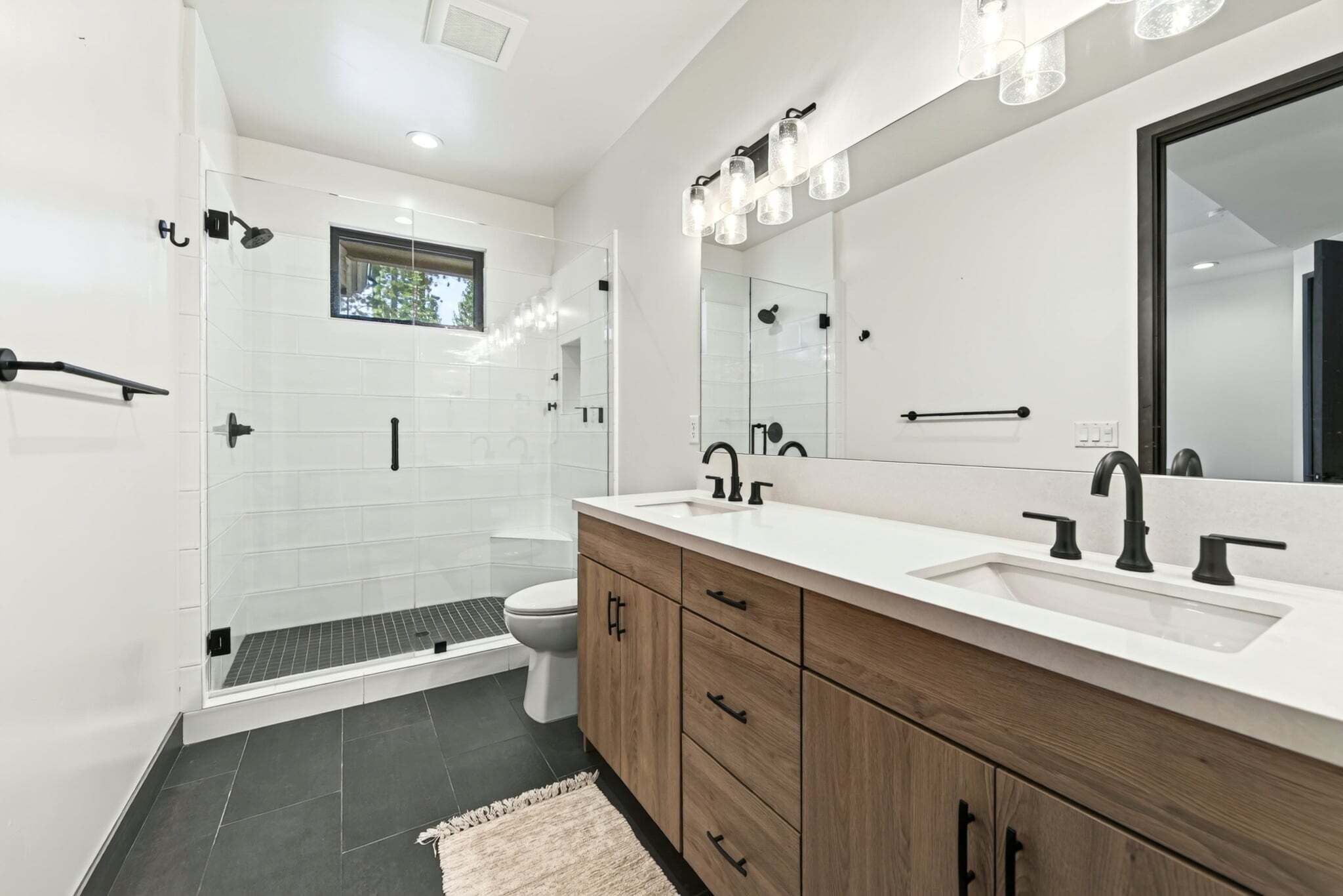 Een moderne badkamer met een inloopdouche, toilet en een wastafel met een grote spiegel.