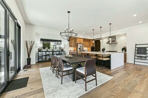 Eine moderne Küche mit einer zentralen Kochinsel, Holzschränken und einem Essbereich mit großem Tisch und Stühlen.