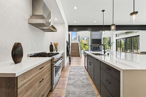 Eine moderne Küche mit einer Kochinsel, integrierten Geräten und Blick auf einen Balkon.