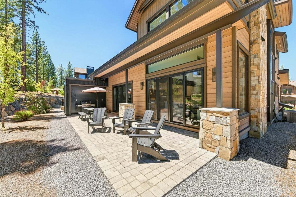 Moderni talo, jossa on patio ja ulkotila, jossa on istuimia sekä kivinen takka.