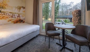 Een slaapkamer met een bed, twee stoelen en een tafel.