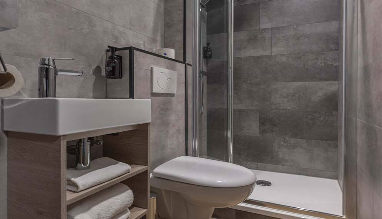 A modern bathroom with a glass shower enclosure, a white sink, and a toilet.