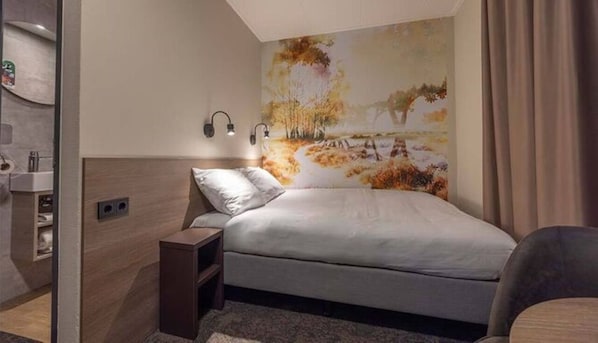Een moderne slaapkamer met een bed, nachtkastje en een wandlamp.