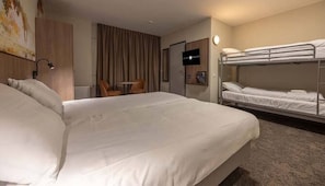 Een hotelkamer met een groot bed, een stapelbed, een bureau en een stoel.